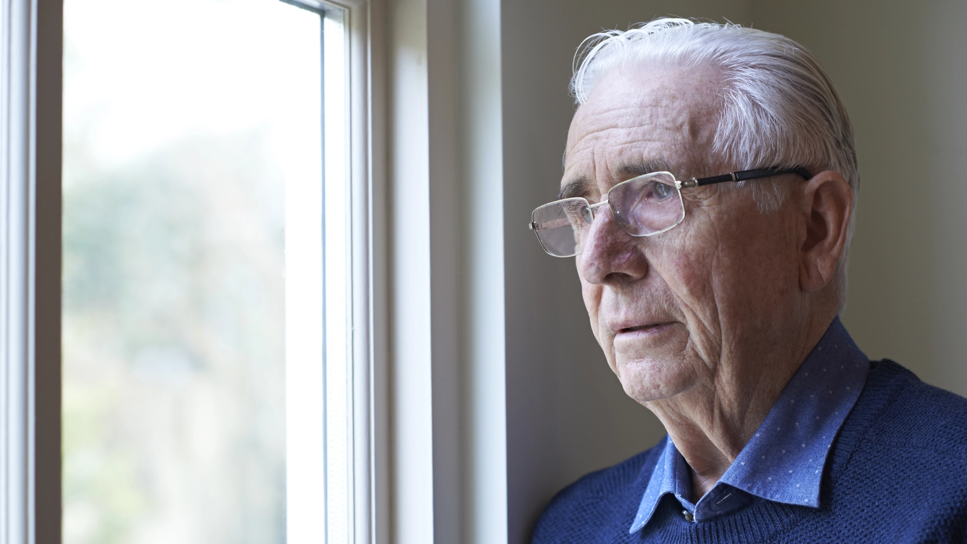 Older man with glasses looking out the window

